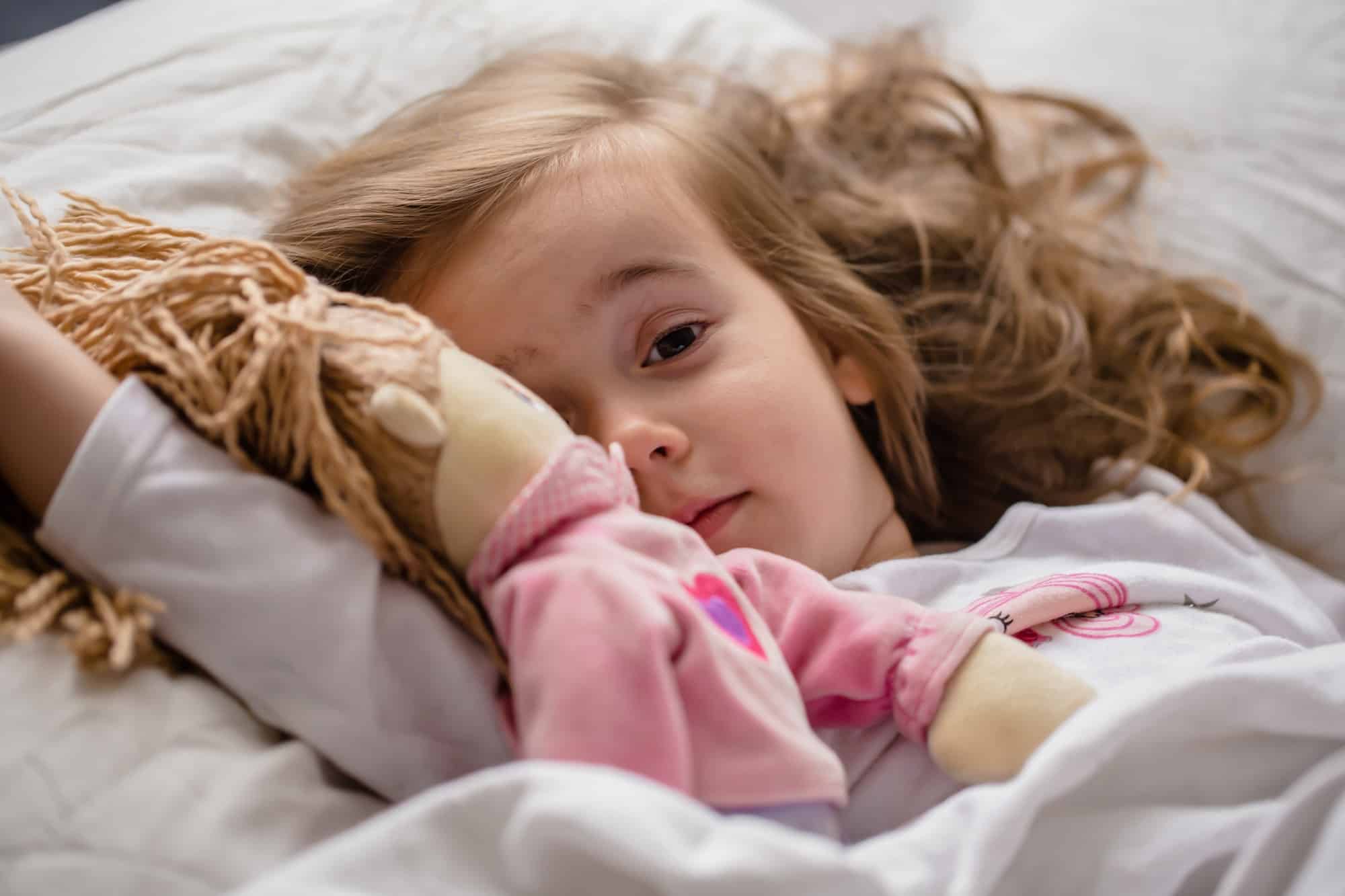 little-girl-falls-asleep-in-bed-with-soft-doll-white.jpg